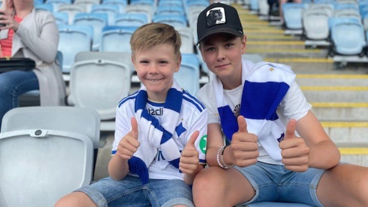 Tim och Vilgot sitter på läktaren vid en fotbollsmatch.